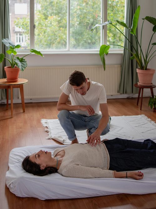 Persoon krijgt drukpuntmassage tijdens een verbonden ademsessie